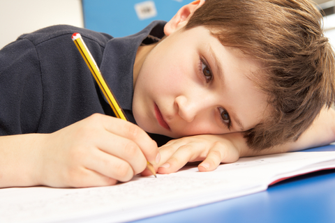 Boy writing with head on table