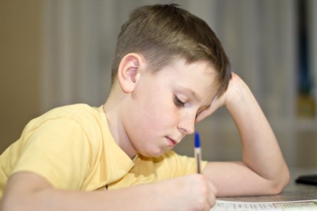 Boy writng head leaning on hand